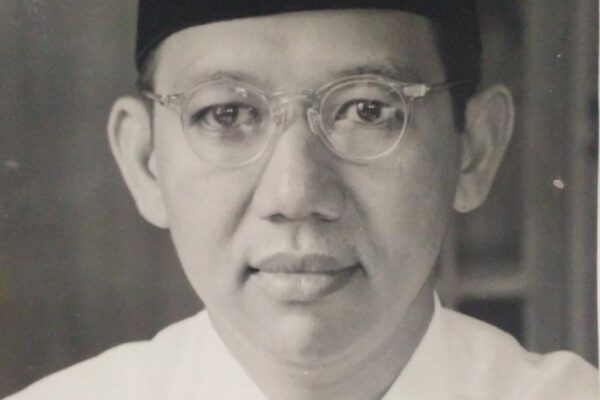 Potret KH Wahid Hasyim mengenakan peci dan kacamata.