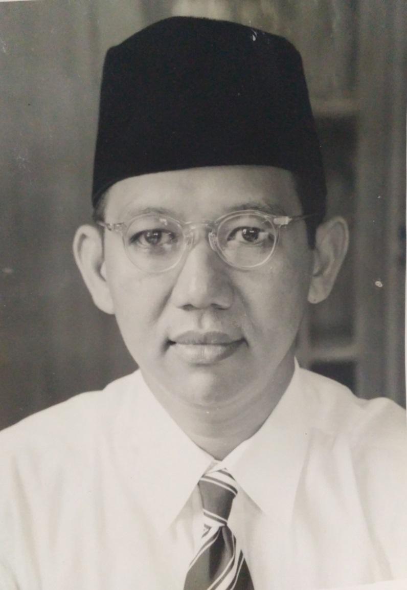 Potret KH Wahid Hasyim mengenakan peci dan kacamata.