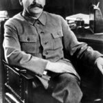Josef Stalin duduk di kursi dengan seragam khas pemimpin Soviet