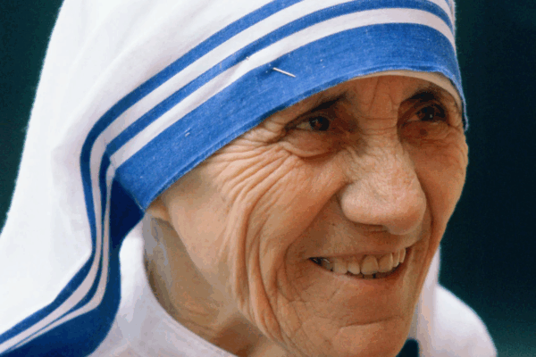 Mother Teresa mengenakan sari putih bergaris biru sambil tersenyum
