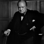 Winston Churchill berdiri dengan ekspresi tegas mengenakan setelan jas gelap