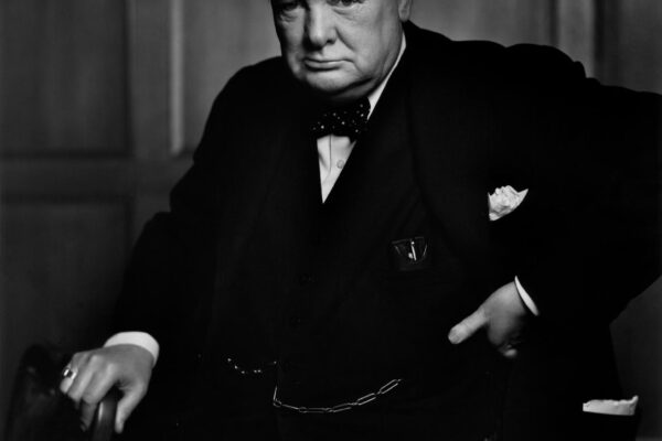 Winston Churchill berdiri dengan ekspresi tegas mengenakan setelan jas gelap