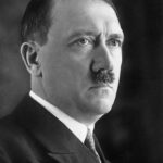 Potret Adolf Hitler mengenakan setelan jas hitam, tampak serius menatap ke arah kanan.