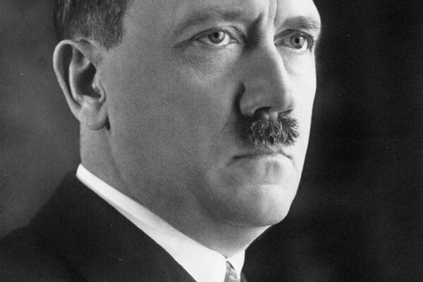 Potret Adolf Hitler mengenakan setelan jas hitam, tampak serius menatap ke arah kanan.